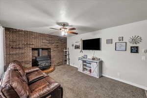 Living room with a wood stove, a ceiling fan, carpet floors, and a textured ceiling