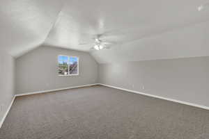 Bonus room featuring vaulted ceiling, carpet, ceiling fan, and a textured ceiling