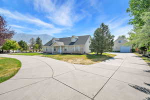 Cape cod home featuring concrete driveway, a mountain view, stone siding, a front lawn, and a garage