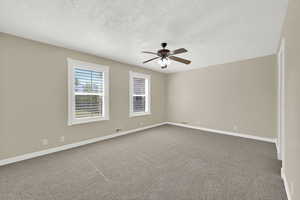 Unfurnished room featuring a textured ceiling, a ceiling fan, and dark colored carpet