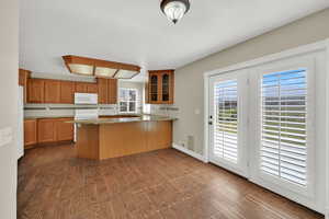 Kitchen featuring white appliances, a peninsula, glass insert cabinets, and decorative backsplash