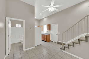 Entrance foyer featuring a high ceiling, a ceiling fan, stairway, healthy amount of natural light, and light tile patterned floors