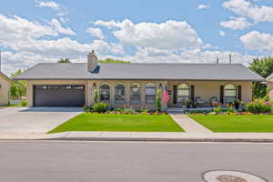 Single story home featuring brick siding, a front lawn, covered porch, and a garage