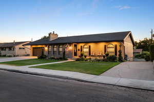 Ranch-style house with concrete driveway, a garage, a front yard, a chimney, and a shingled roof