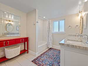 Bathroom with shower / bath combo, a textured ceiling, and double vanity