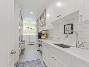 Kitchen with washer and dryer, open shelves, white cabinets, backsplash, and recessed lighting