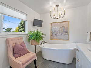 Bathroom with a freestanding bath, vanity, a chandelier, and tile patterned flooring