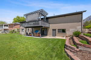Rear view of property with a lawn, a patio, a wooden deck, and brick siding