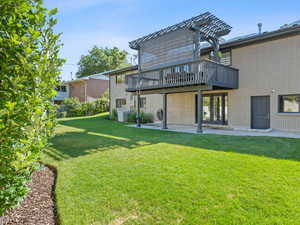 Rear view of property featuring a yard, a deck, and a patio