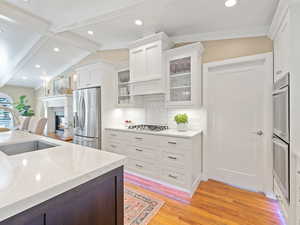 Kitchen with appliances with stainless steel finishes, light wood-type flooring, white cabinetry, backsplash, and recessed lighting