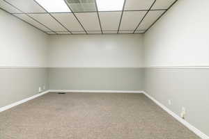 Carpeted empty room with baseboards and a paneled ceiling