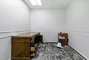 Unfurnished office with a paneled ceiling and baseboards