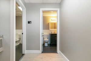 Hallway featuring light wood-style flooring and a drop ceiling