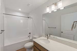 Full bath featuring vanity, washtub / shower combination, and wood finished floors