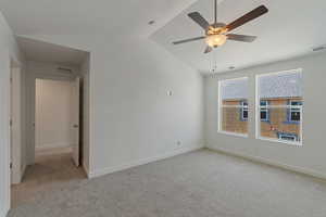 Unfurnished room featuring lofted ceiling, light carpet, and a ceiling fan