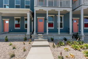 Doorway to property featuring covered porch, stucco siding, and a balcony