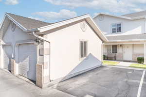 View of side of home featuring stucco siding, roof with shingles, and a garage