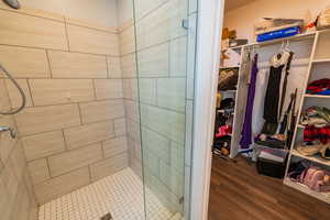 Bathroom with a stall shower, wood finished floors, and a walk in closet