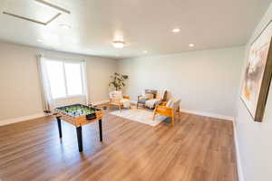 Game room featuring light wood-type flooring, recessed lighting, attic access, and a textured ceiling