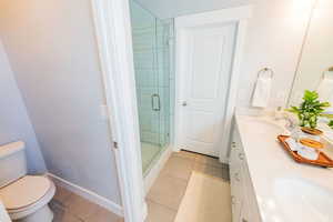 Bathroom featuring tile patterned flooring, double vanity, and a stall shower