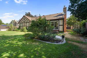 Back of house with stucco siding and a chimney