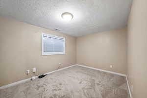 Empty room featuring carpet flooring and a textured ceiling
