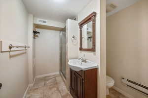 Full bath featuring baseboard heating, vanity, and a stall shower