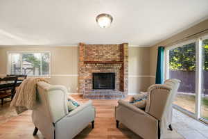 Living room featuring ornamental molding, light wood-style flooring, a fireplace, and a textured ceiling