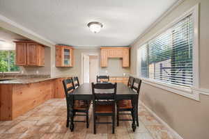 Dining area with plenty of natural light, a textured ceiling, crown molding, and light stone finish floors