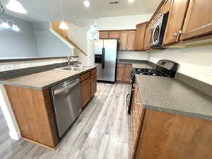 Kitchen featuring stainless steel appliances, dark countertops, and brown cabinetry