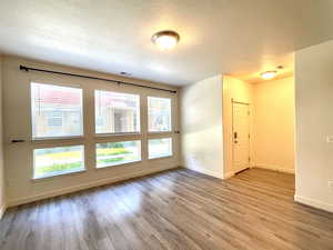 Unfurnished room with wood finished floors and a textured ceiling