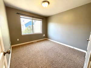Carpeted spare room featuring baseboards