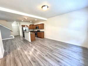 Kitchen featuring appliances with stainless steel finishes, open floor plan, wood finished floors, a kitchen island, and a textured ceiling