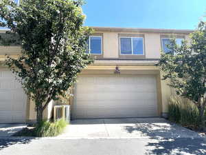 View of front of property featuring stucco siding, a garage, and driveway