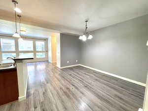 Unfurnished dining area with wood finished floors and a chandelier