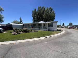 Manufactured / mobile home featuring covered porch and a front lawn