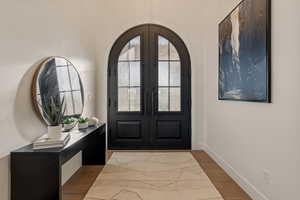 Entrance foyer featuring wood finished floors, arched walkways, and french doors
