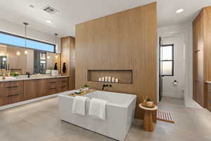 Full bathroom featuring a freestanding tub, vanity, light tile patterned floors, and recessed lighting