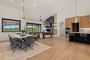 Dining space featuring high vaulted ceiling, a chandelier, light wood-style floors, recessed lighting, and a ceiling fan