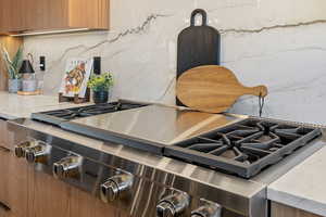 Kitchen view of light stone countertops, tasteful backsplash, stainless steel appliances, and modern cabinets