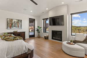 Bedroom with lofted ceiling, light wood-type flooring, a fireplace, recessed lighting, and ceiling fan