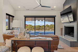 Living room featuring light wood finished floors, a tiled fireplace, plenty of natural light, recessed lighting, and ceiling fan
