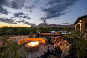 Patio terrace at dusk with an outdoor fire pit, a patio, a jacuzzi, and a mountain view