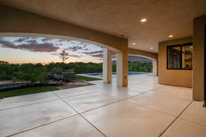 Patio terrace at dusk featuring a patio area and an outdoor pool