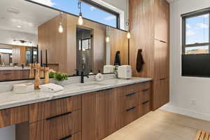 Full bath with healthy amount of natural light, vanity, light tile patterned flooring, and a shower stall