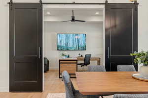 Office space with a barn door, light wood-style flooring, a ceiling fan, and recessed lighting