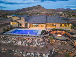 View of pool with a fire pit, a fenced backyard, a mountain view, a pool with connected hot tub, and a patio
