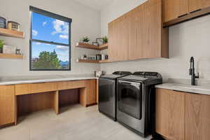 Laundry area featuring washing machine and clothes dryer, cabinet space, and light tile patterned floors