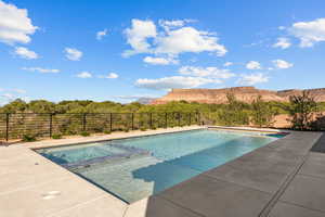 View of swimming pool with a pool with connected hot tub, a patio, a fenced backyard, a mountain view, and a forest view