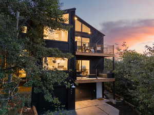 Back of house with a balcony, an attached garage, and concrete driveway